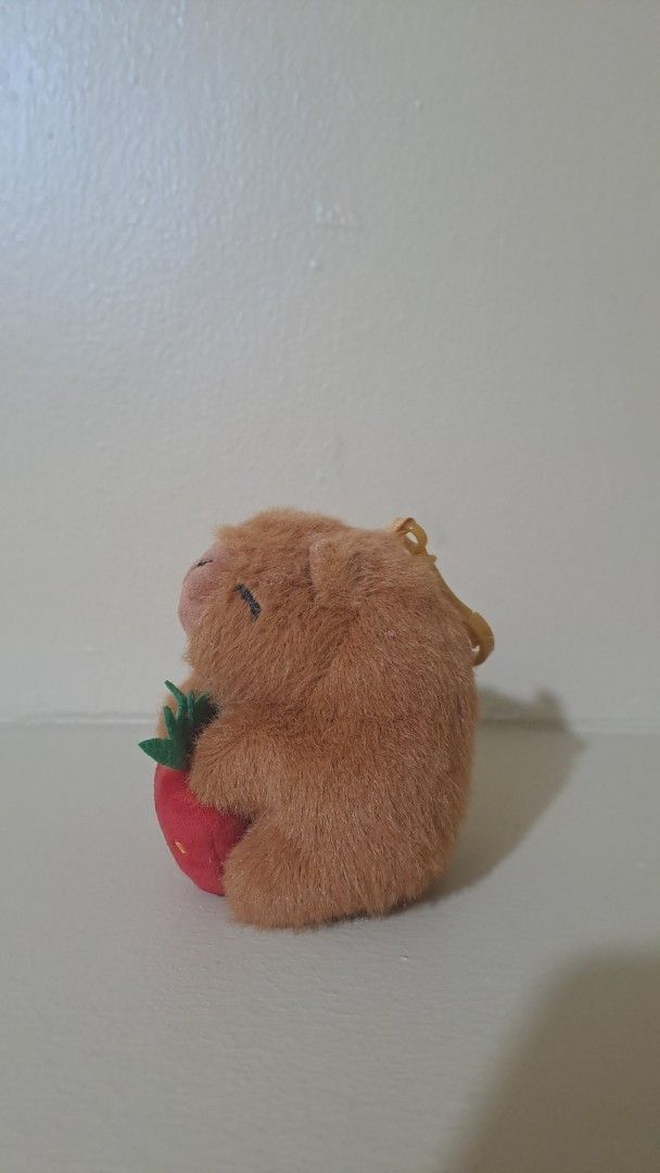 Capybara keychain holding a strawberry (Category: Character Goods) located in Muntinlupa City. Submitted by repurp0se (Listing ID 1463275610, Image 3). Description: Pls adopt this capybara keychain!!! - Great condition - Might be a bit dusty but thats all Rfs: Need funds for school .