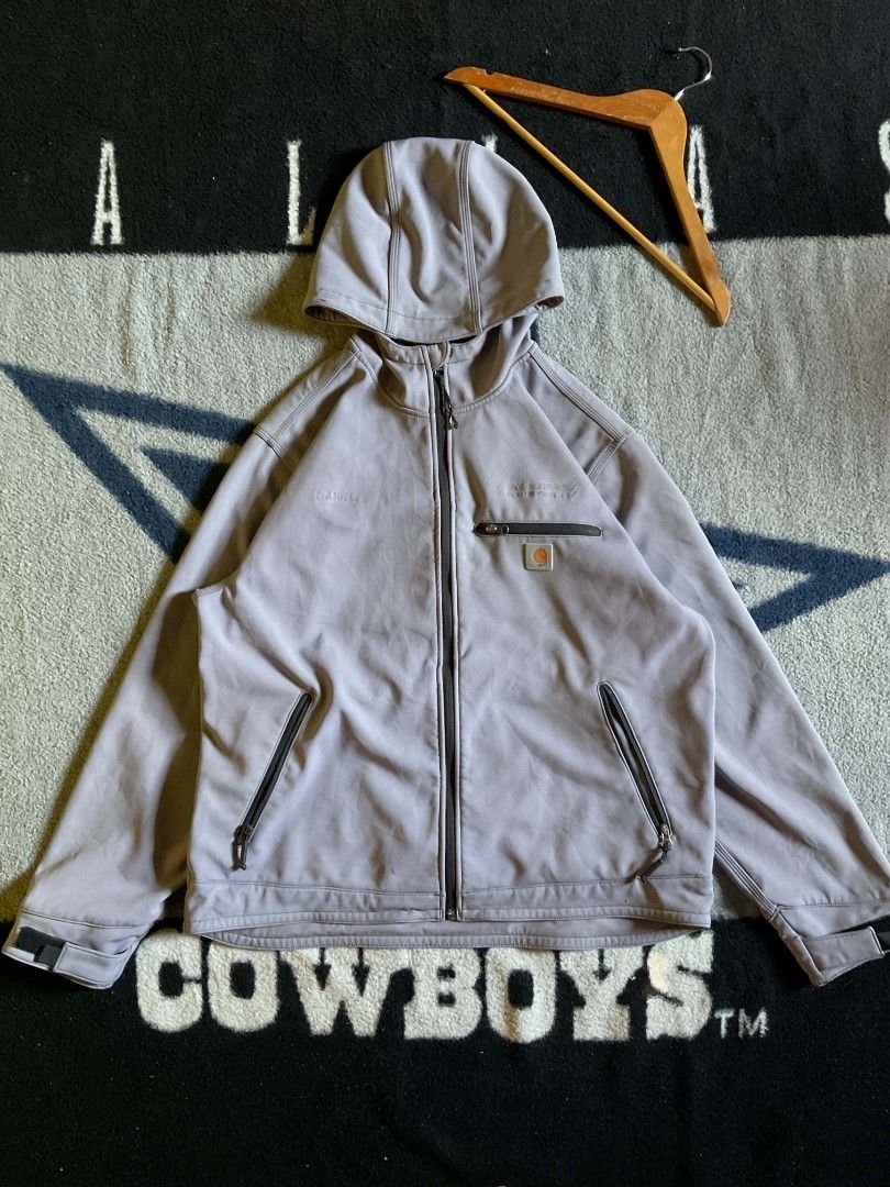 Carhartt Softshell Full Zip Hoodie (Category: Coats, Jackets and Outerwear) located in San Pedro. Submitted by vinasjohna38754 (Listing ID 1463157834, Image 1). Description: - Carhartt softshell hoodie - Full zip closure - Chest pocket and two side pockets - Attached hood - Versatile for outdoor activities or casual wear - Unique light grey/purple color - Features Carhartt branding on the chest.
