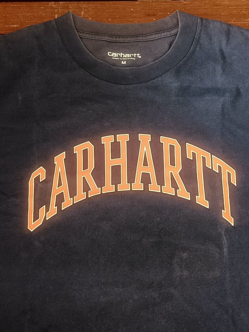 Carhartt Work In Progress Navy T-Shirt Size M (Category: Tshirts & Polo Shirts ) located in Calamba. Submitted by sulitshopaholic (Listing ID 1463323608, Image 3). Description: - Navy blue Carhartt WIP T-shirt - Features 'CARHARTT' graphic in orange across the chest - Size: Medium (M) - Dimes: 28L X 21W - Material: 100% Cotton - Origin: Made in Cambodia - Ideal for casual wear - Needs wash due to prolonged storage, rarely worn.