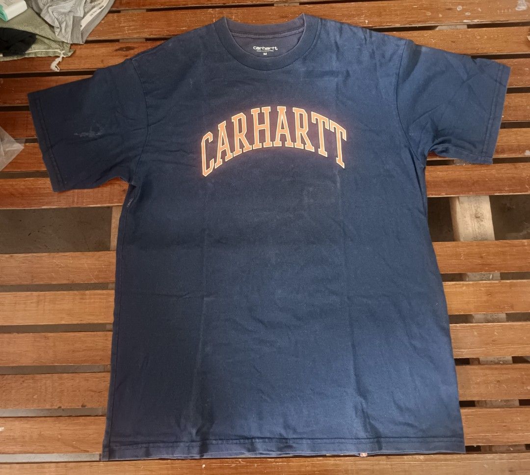 Carhartt Work In Progress Navy T-Shirt Size M (Category: Tshirts & Polo Shirts ) located in Calamba. Submitted by sulitshopaholic (Listing ID 1463323608, Image 1). Description: - Navy blue Carhartt WIP T-shirt - Features 'CARHARTT' graphic in orange across the chest - Size: Medium (M) - Dimes: 28L X 21W - Material: 100% Cotton - Origin: Made in Cambodia - Ideal for casual wear - Needs wash due to prolonged storage, rarely worn.