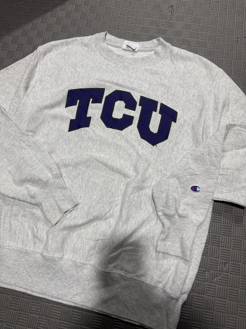 Champion TCU Reverse Weave Crewneck Sweatshirt Medium (Category: Coats, Jackets and Outerwear) located in Baguio. Submitted by MysticVaultPh (Listing ID 1463291633, Image 2). Description: - Grey Champion Reverse Weave sweatshirt - Features large navy blue 'TCU' graphic on the front - Classic crewneck style with long sleeves - Small Champion 'C' logo on the left sleeve cuff - Ideal for TCU fans or casual wear.