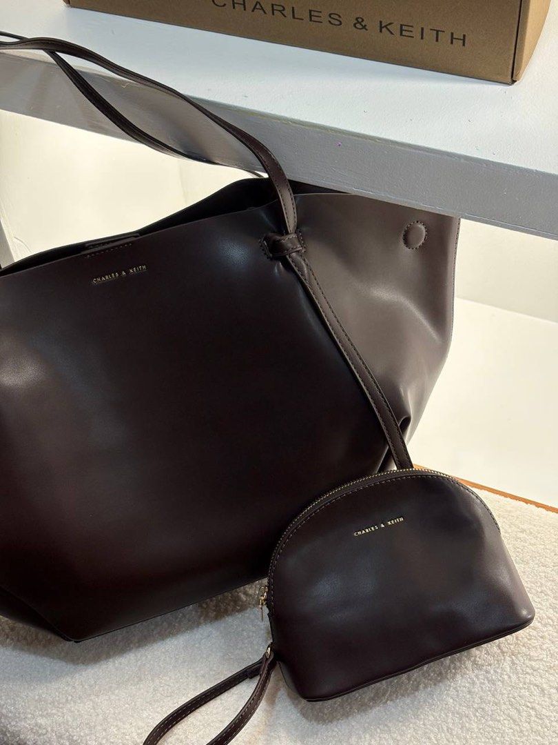 Charles & Keith Calla Tote Bag with Pouch (Category: Tote Bags) located in Manila. Submitted by cher.ish.ed (Listing ID 1463261345, Image 3). Description: - Charles & Keith tote bag and matching pouch. - Colors: Black & Espresso Brown - Unique tote shape with side tie details. - Includes a small zip-around pouch. - Ideal for everyday use or travel..