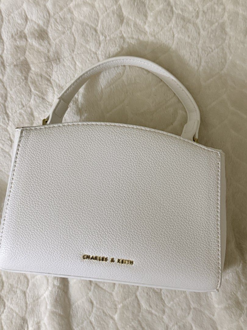 Charles & Keith White Top Handle Bag (Category: Shoulder Bags) located in Quezon City. Submitted by unforgettwble. (Listing ID 1463302726, Image 2). Description: - Cute white textured handbag - Gold clasp closure on front flap - Matching textured top handle - Small and compact size - Ideal for carrying essentials.