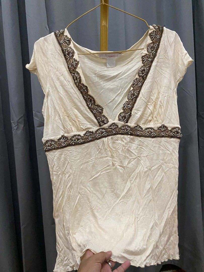 Cream Beaded V-Neck Top (Category: Sleeveless) located in Malasiqui. Submitted by finnley26 (Listing ID 1463166714, Image 1). Description: - Elegant cream-colored top with short sleeves. - Flattering V-neckline adorned with intricate brown and gold beadwork. - Beaded band accentuates the empire waist. - Unique slightly crinkled fabric texture..