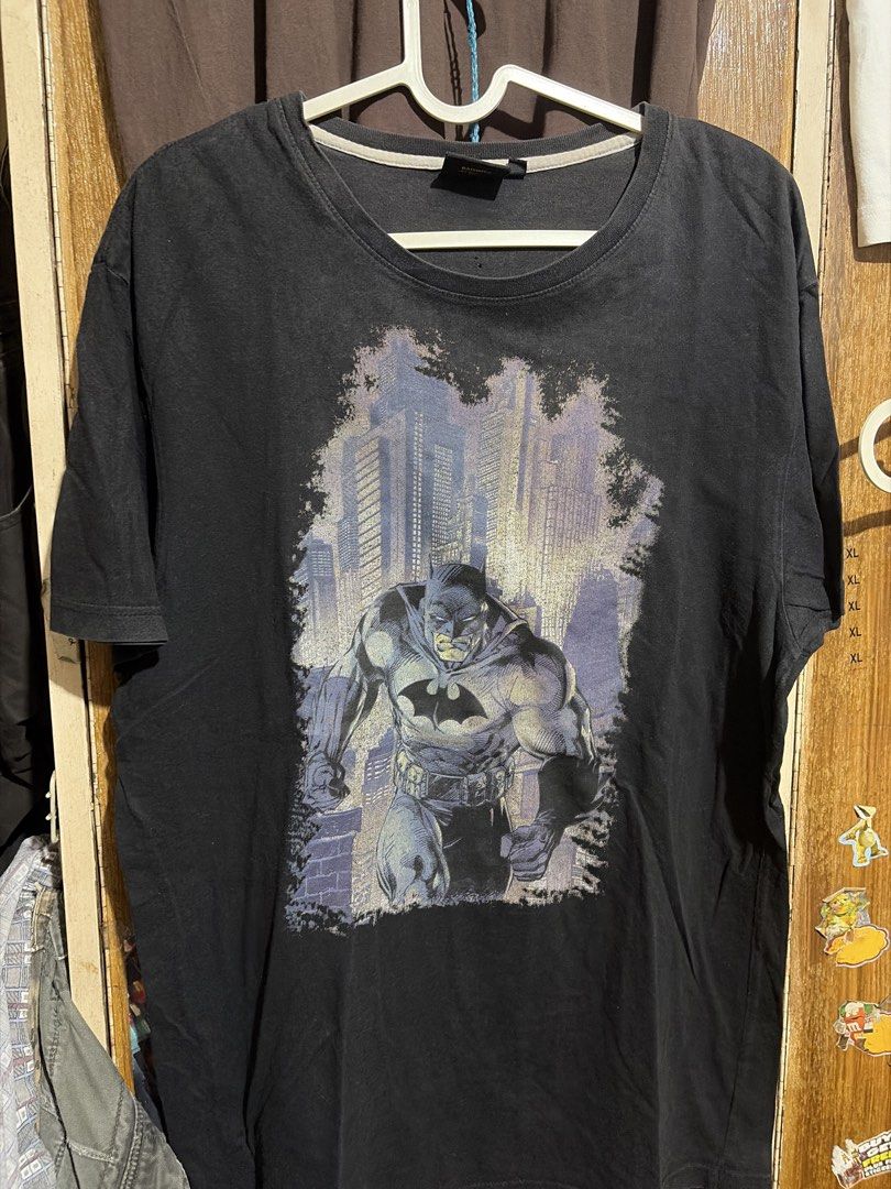 [DC COMICS TEE] Vintage Batman T-Shirt (Category: Tshirts & Polo Shirts ) located in Imus. Submitted by frootiloots4103 (Listing ID 1463170321, Image 1). Description: - Black t-shirt with a cool Batman graphic print. - Features the iconic Batman logo on the back. - Approximate measurements: 22 inches wide by 30 inches long. - Issue: Pinhole (check photo for reference) - Note: There are a couple of small holes on the front, as pictured. - Ideal fo