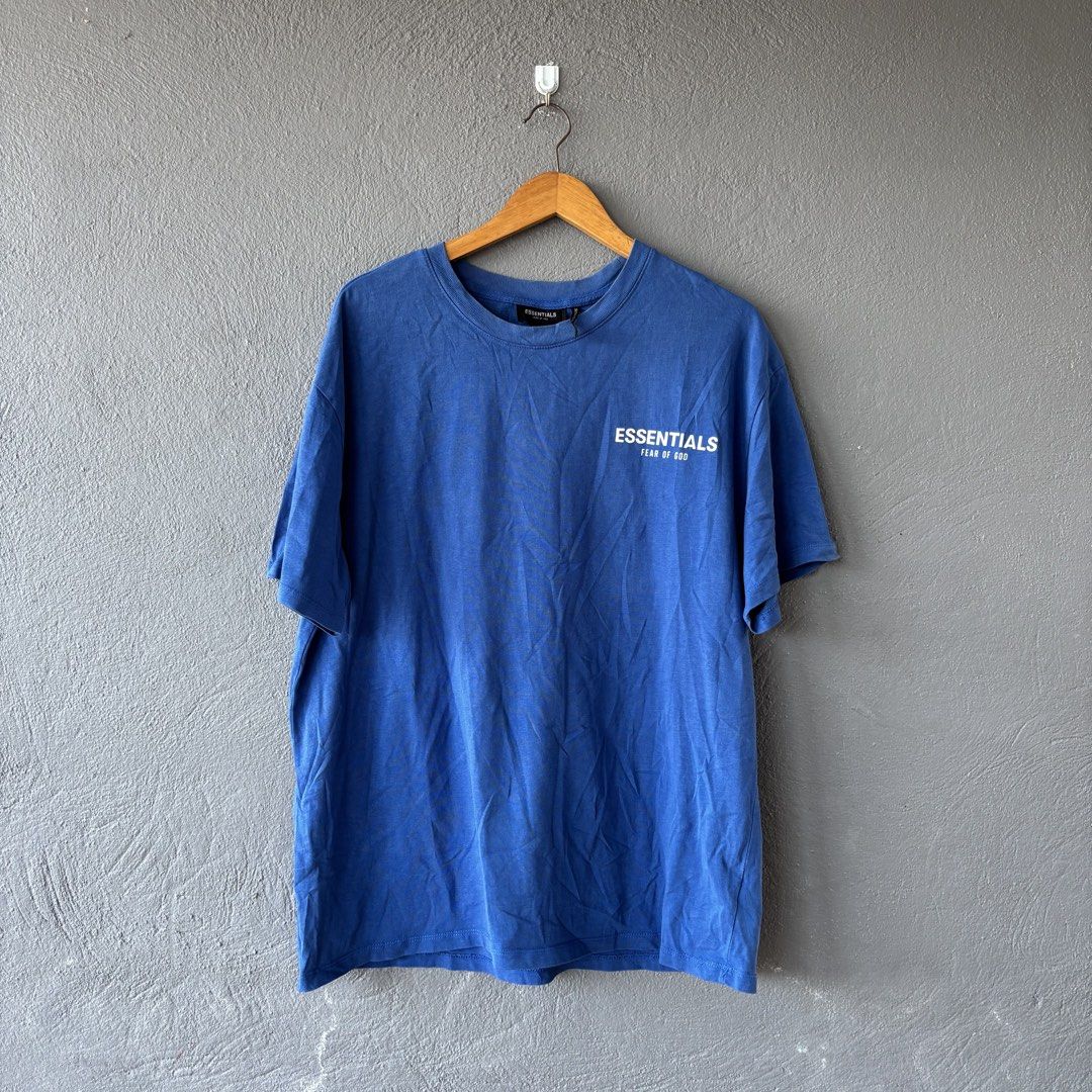 Essential tee (Category: Tshirts & Polo Shirts ) located in San Fernando. Submitted by diff.thr1ft (Listing ID 1463244111, Image 1). Description: - Brand: ESSENTIALS - Color: Blue - Material: 100% Cotton - Size: M on tag fit Large (L) - Front Design: ESSENTIALS FEAR OF GOD - Back Design: Gershaw - Condition: Good.