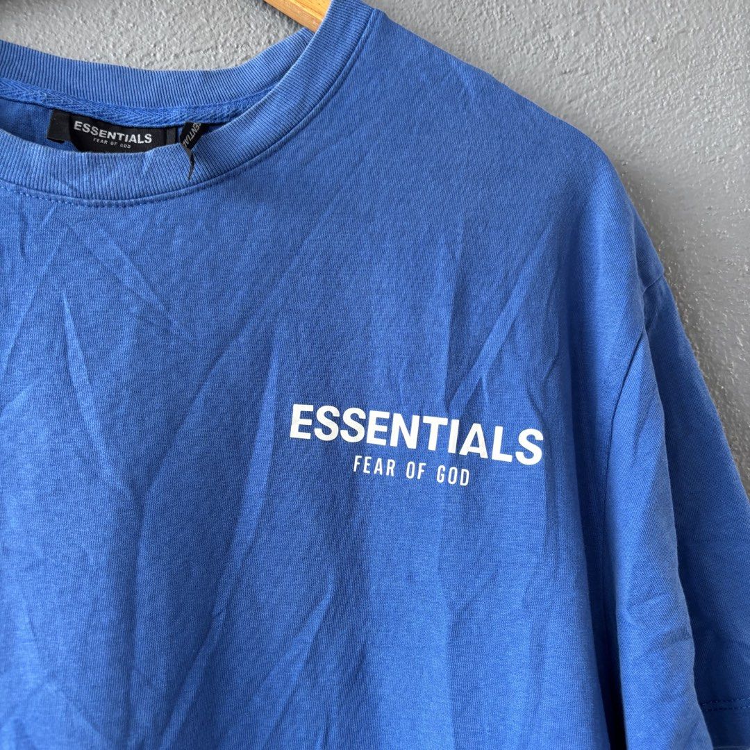 Essential tee (Category: Tshirts & Polo Shirts ) located in San Fernando. Submitted by diff.thr1ft (Listing ID 1463244111, Image 2). Description: - Brand: ESSENTIALS - Color: Blue - Material: 100% Cotton - Size: M on tag fit Large (L) - Front Design: ESSENTIALS FEAR OF GOD - Back Design: Gershaw - Condition: Good.