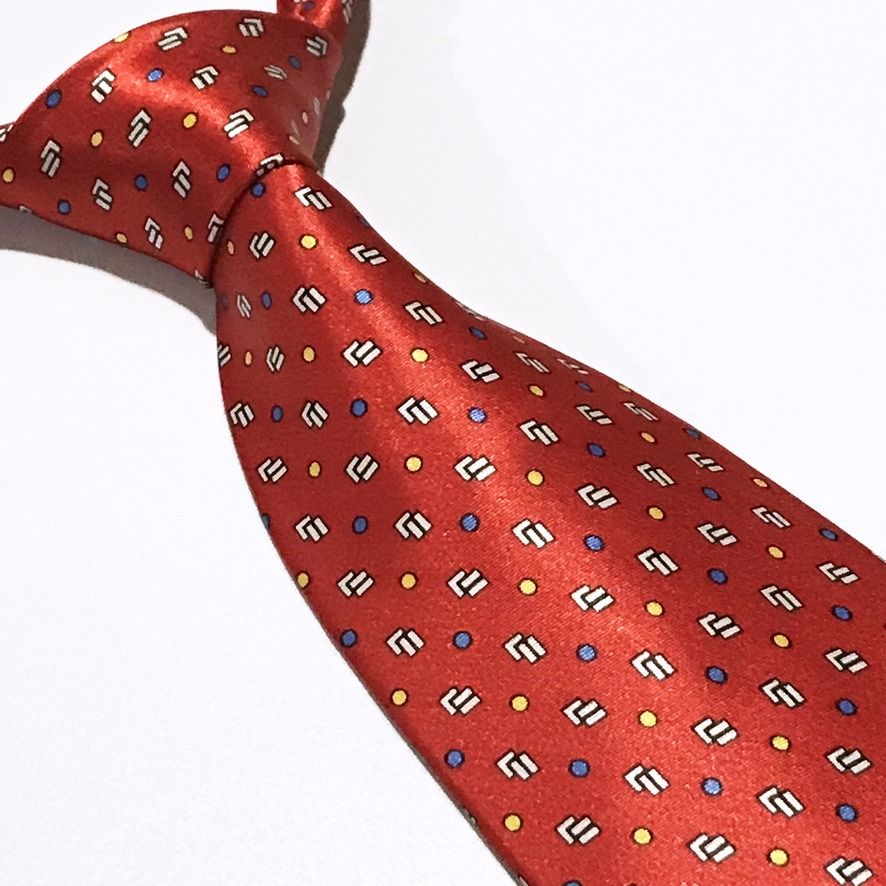 Goldlion Repeating Pattern Hand Made Red Neck Tie (Category: Ties) located in Taguig. Submitted by retrogaze (Listing ID 1463246308, Image 1). Description: This handmade 100% silk necktie by Goldlion features a vibrant red base with a smooth, luxurious finish. The body displays a dense geometric layout of repeating white and black stepped block motifs, interspersed with an evenly spaced grid of micro yellow and blue polka dots. Brand Overview: Fo