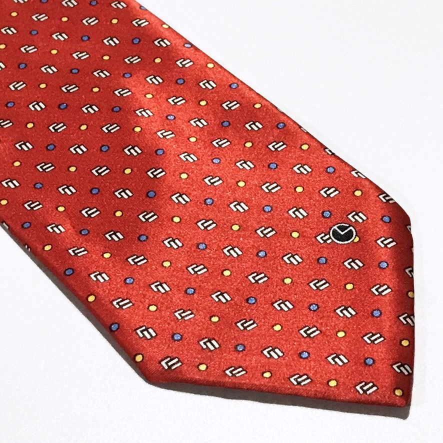 Goldlion Repeating Pattern Hand Made Red Neck Tie (Category: Ties) located in Taguig. Submitted by retrogaze (Listing ID 1463246308, Image 2). Description: This handmade 100% silk necktie by Goldlion features a vibrant red base with a smooth, luxurious finish. The body displays a dense geometric layout of repeating white and black stepped block motifs, interspersed with an evenly spaced grid of micro yellow and blue polka dots. Brand Overview: Fo
