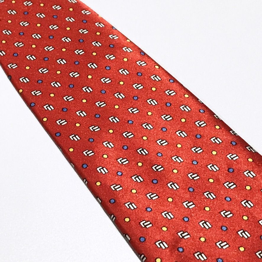 Goldlion Repeating Pattern Hand Made Red Neck Tie (Category: Ties) located in Taguig. Submitted by retrogaze (Listing ID 1463246308, Image 3). Description: This handmade 100% silk necktie by Goldlion features a vibrant red base with a smooth, luxurious finish. The body displays a dense geometric layout of repeating white and black stepped block motifs, interspersed with an evenly spaced grid of micro yellow and blue polka dots. Brand Overview: Fo