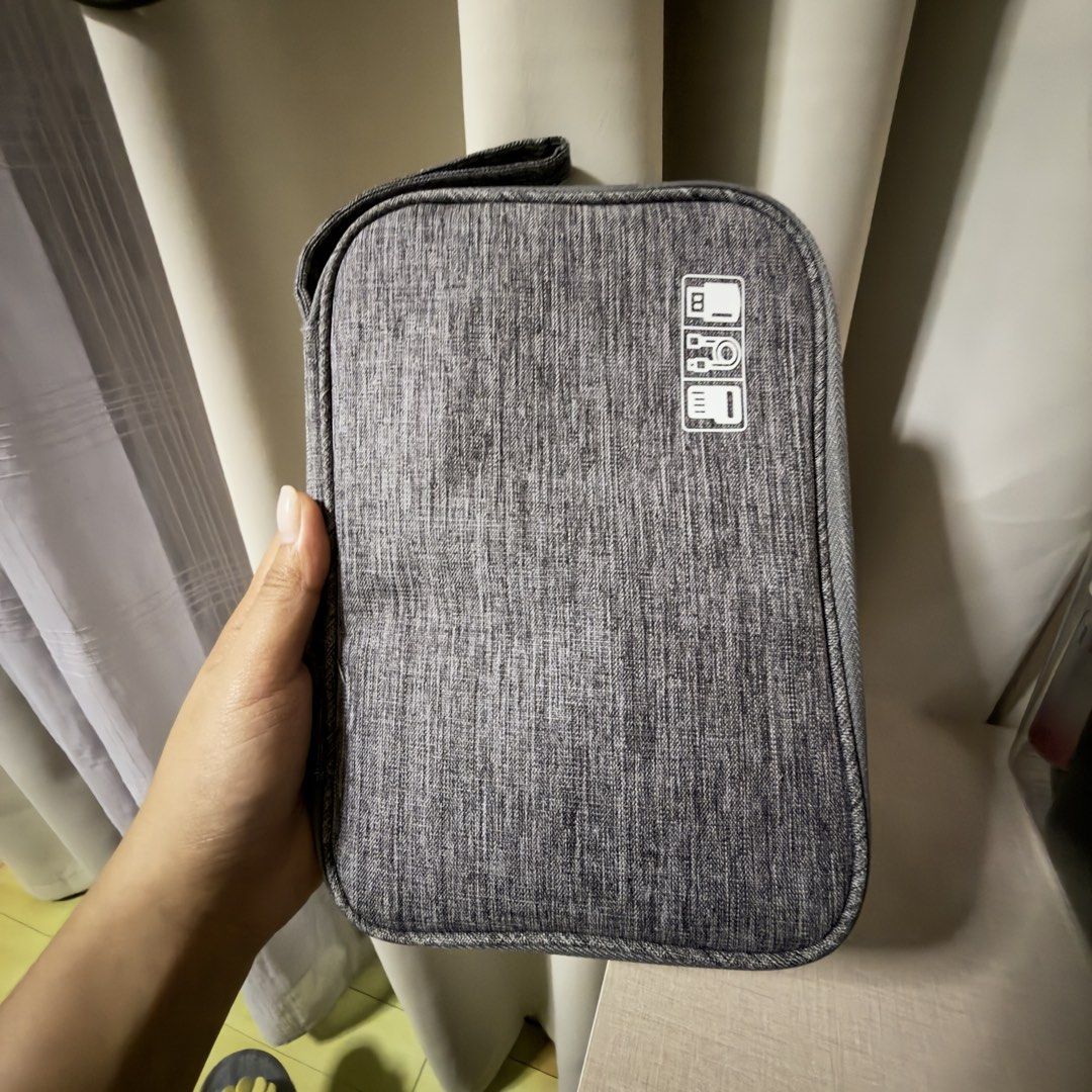 Grey Electronics Organizer Bag for Cables and Accessories (Category: Belt bags, Clutches and Pouches) located in Cebu City. Submitted by eynjlin (Listing ID 1463286769, Image 2). Description: - Grey travel organizer bag - Ideal for keeping cables, chargers, and small electronics tidy - Multiple compartments and elastic straps inside for organization - Secure zipper closure - Compact and portable design - Durable fabric exterior - Perfect for trav
