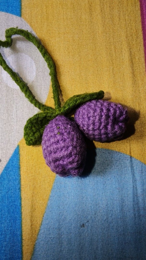 Crocheted Purple Tulips Charm (Category: Handmade Craft) located in Manila. Submitted by rare.elieli (Listing ID 1463168811, Image 1). Description: - Cute handmade charm - Resembles two purple plums or berries with green leaves and stem - Made from yarn - Ideal for DIY crafts or as a keychain accessory - Unique piece.