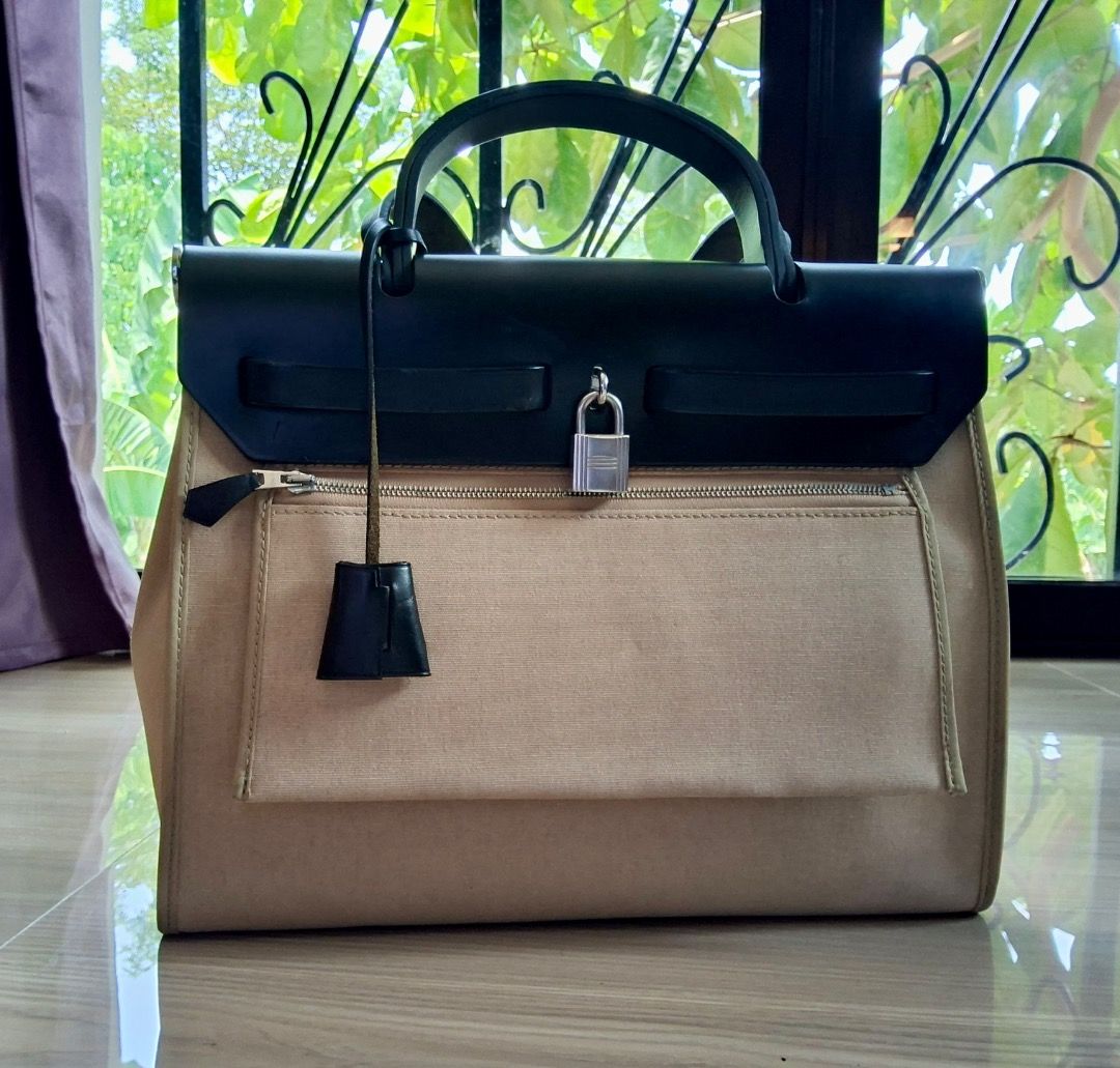Hermes Herbag (Category: Luxury Bags & Wallets) located in Albuera. Submitted by zaraofdammam09 (Listing ID 1463199401, Image 2). Description: - Classic - Durable canvas body - Black leather trim and handles - Comes with padlock and key - Exterior zippered pocket - Interior pouch pocket - Versatile for everyday or special occasions.