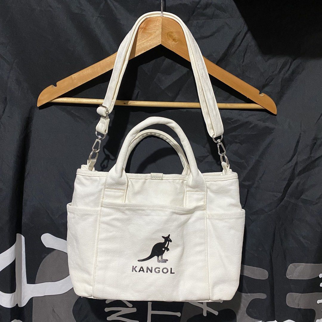 Kangol White Canvas Tote Bag with Pockets (Category: Tote Bags) located in Villasis. Submitted by thriftngrind (Listing ID 1463240518, Image 1). Description: - Measurements: 11.5 (Width) / 8.5 (Length) - White canvas tote bag from Kangol - Features classic kangaroo logo on the front - Multiple exterior pockets for easy access - Interior pockets for organization - with Top handles and detachable and adjustable shoulder strap - Ideal for everyday u