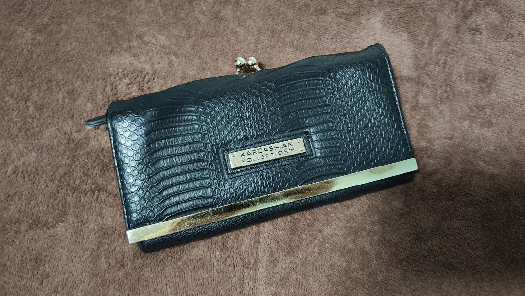 Kardashian Collection Black Textured Wallet (Category: Wallets & Card holders) located in Manila. Submitted by serenitycarlylle (Listing ID 1463300975, Image 1). Description: - Kardashian Collection black wallet - Textured exterior with gold trim detail - Secure clasp closure - Multiple card slots - Clear ID window - Zippered compartment for extra storage - Ideal for keeping your essentials organized.