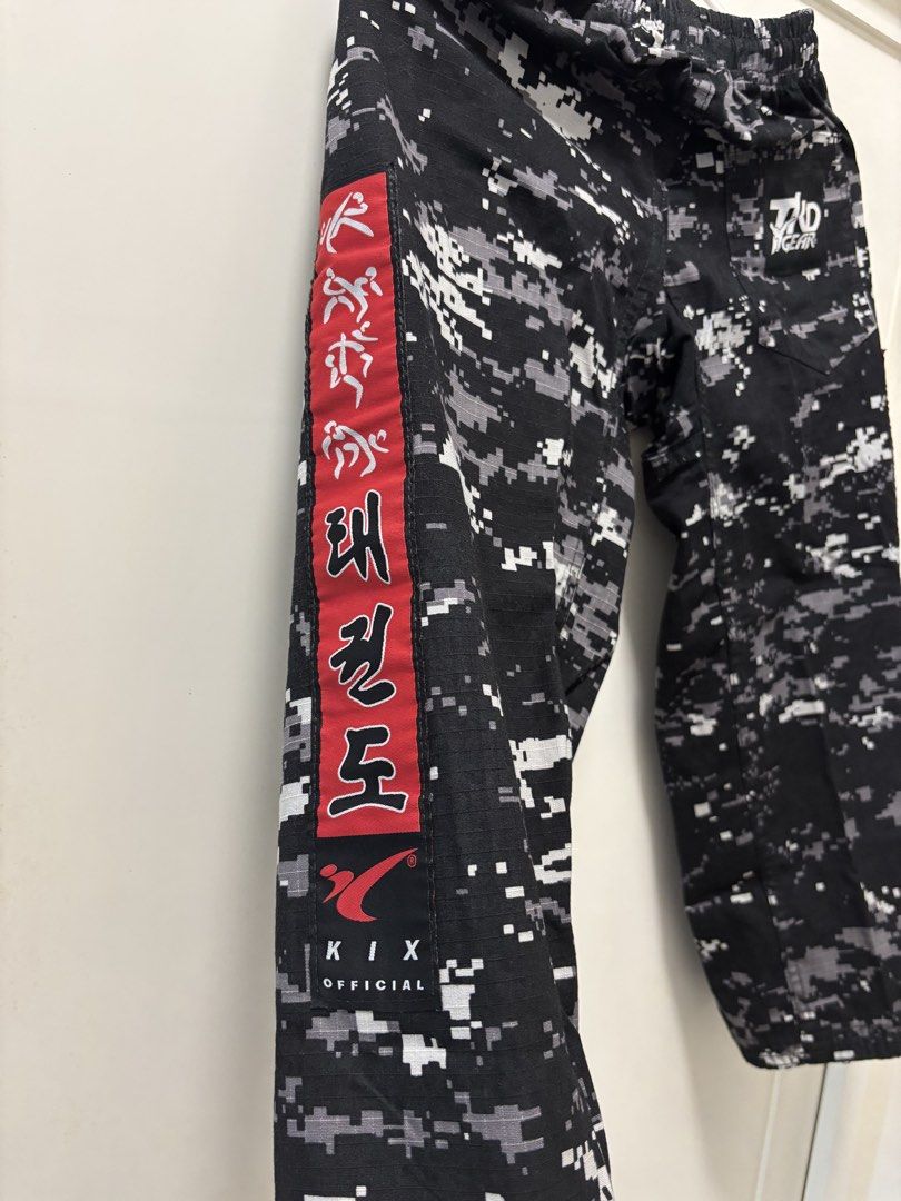 KIX Camouflage Taekwondo Training Pants - Size 4 (Category: Other Sports Equipment and Supplies) located in Manila. Submitted by mrstinq (Listing ID 1463259792, Image 3). Description: - Stylish black and grey digital camouflage pattern - Features a bold red stripe with Korean text on the side - Comfortable elastic waistband for a secure fit - KIX TKD GEAR branding on the back - Ideal for Taekwondo training sessions.