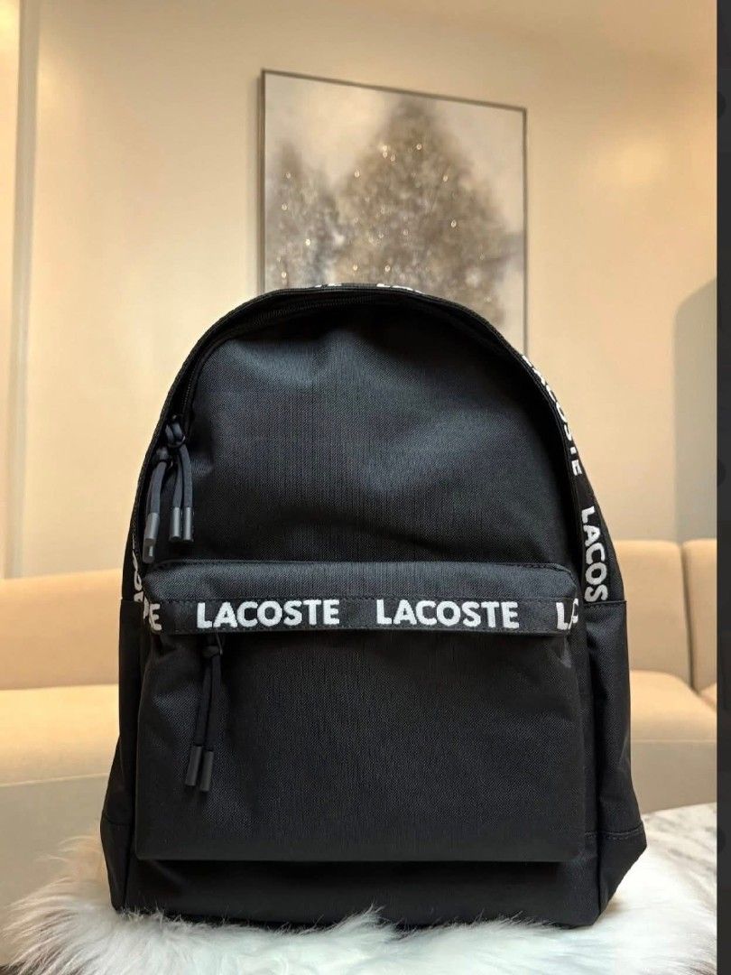 Lacoste Black Backpack with Logo Tape (Category: Luxury Bags & Wallets) located in Makati City. Submitted by time.flip (Listing ID 1463142596, Image 1). Description: - Classic black Lacoste backpack - Signature Lacoste logo tape on front pocket and straps - Convenient front zip pocket - Spacious main compartment - Zippers with easy-pull tabs - Standard backpack size, ideal for everyday carry.