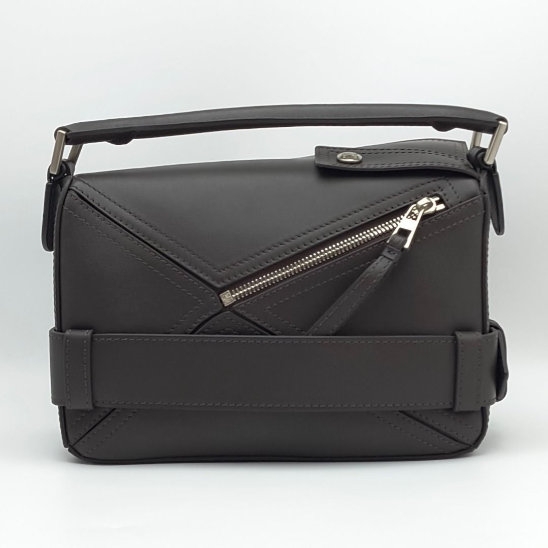 Loewe Puzzle Biker Small Bag Dark Brown (Category: Luxury Bags & Wallets) located in Cebu City. Submitted by theluxxaffair (Listing ID 1463298622, Image 3). Description: Loewe Puzzle Biker Small bag in dark brown shiny calfskin leather with silver-tone hardware. Features the signature Puzzle construction, biker-inspired buckle belt, top handle and detachable shoulder strap. Finished with zip closure and embossed Loewe Anagram logo. Length: 25 cm 