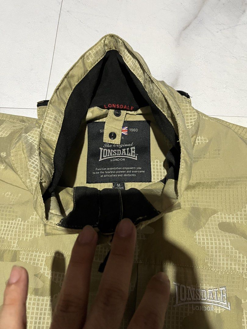 Lonsdale London Camo Jacket (Category: Coats, Jackets and Outerwear) located in Cavite. Submitted by christianzuuu (Listing ID 1463130645, Image 2). Description: - Lonsdale London jacket - Stylish camouflage pattern - Built-in hood in collar - Multiple front pockets for storage - Lined interior with Lonsdale branding - Size: Medium (M) - Ideal for outdoor activities and everyday wear.