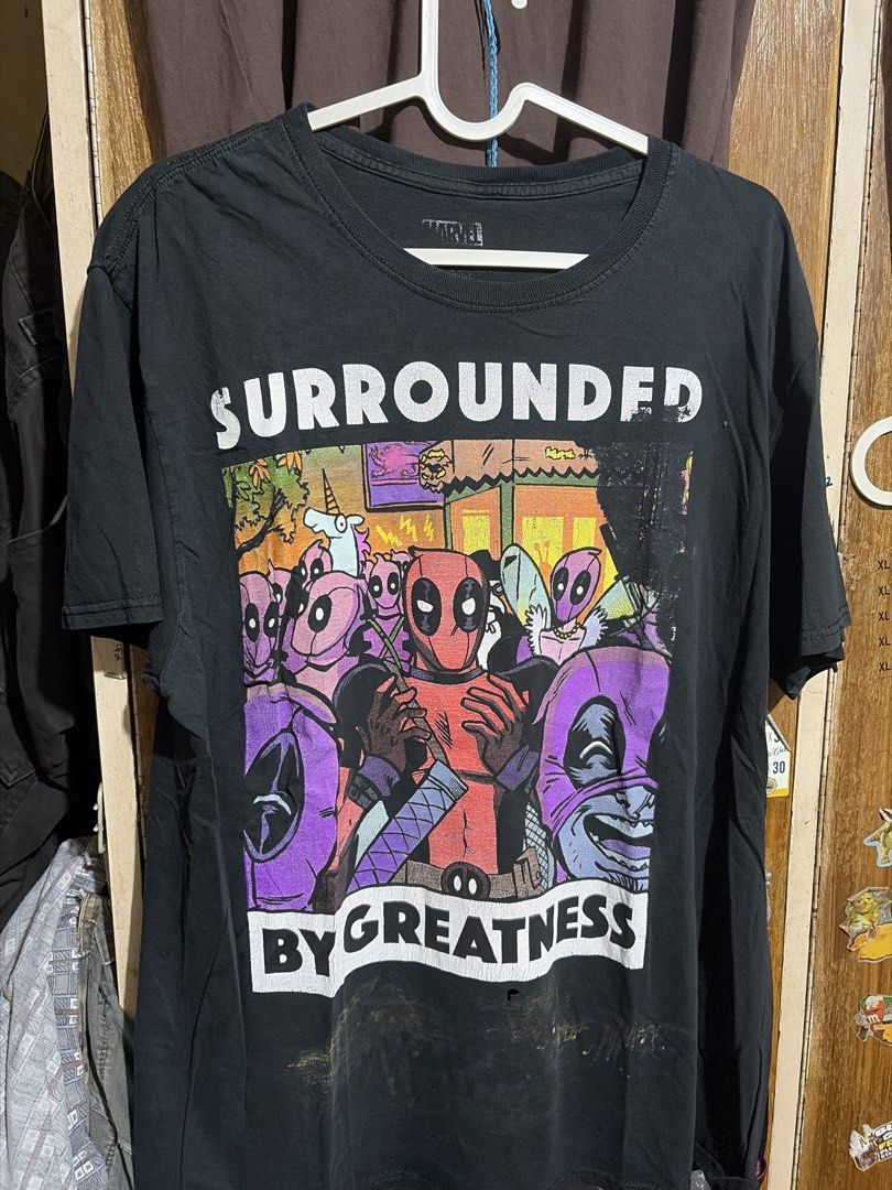 [MARVEL TEE] Marvel Deadpool "Surrounded by Greatness" T-Shirt (Category: Tshirts & Polo Shirts ) located in Imus. Submitted by frootiloots4103 (Listing ID 1463170320, Image 1). Description: - Marvel t-shirt featuring Deadpool and friends - Graphic: "Surrounded by Greatness" - Size: 24x28 inches - Issue: Bleach Stain and Fingerhole - Condition: Small hole and marks on the front bottom (please check photos for details) - Ideal for any Marvel fan.