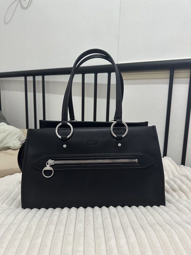 Medium Celys Top Handle Bag (Category: Tote Bags) located in Manila. Submitted by ana_south (Listing ID 1463162677, Image 2). Description: - Classic black Lacoste tote bag - Features silver hardware details (zippers, ring accents) - Main compartment with zip closure - Two top handles for carrying - Simple and chic design - Ideal for everyday use or work RFS: not my preference anymore.