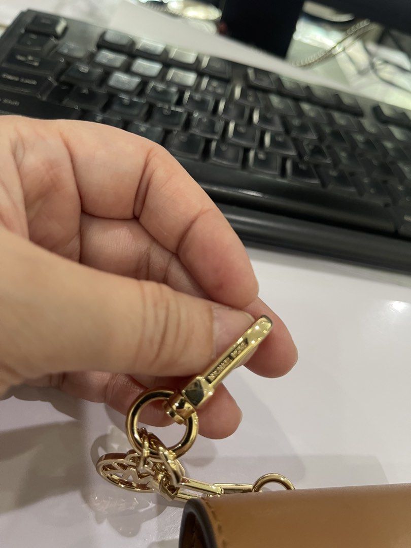 Michael Kors Monogram Keychain Pouch (Category: Luxury Bags & Wallets) located in Paranaque City. Submitted by twinmanila (Listing ID 1463123914, Image 2). Description: - Authentic Michael Kors keychain pouch - Classic MK monogram print in brown and tan - Gold-tone hardware with secure clasp and ring - Small snap closure for easy access - Ideal for storing cards, coins, or other small essentials - Versatile: attach to your handbag, backpack, or k