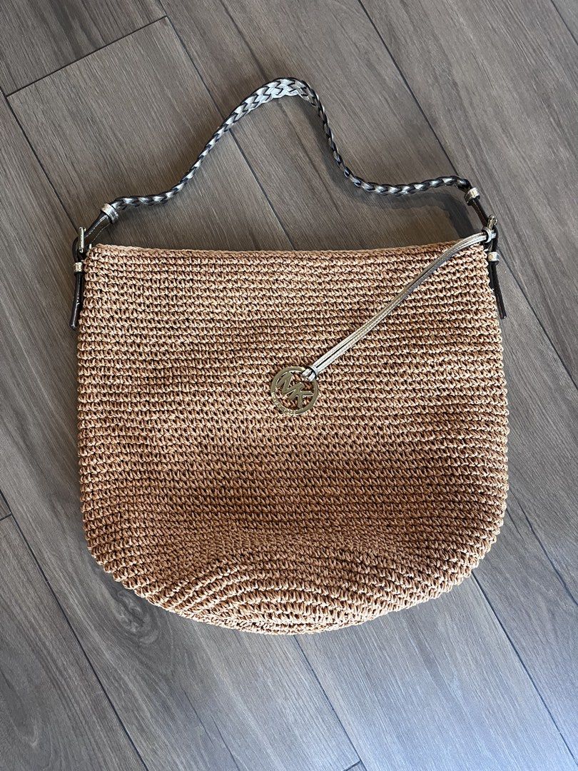 Michael Kors Straw Shoulder Bag with MK Charm (Category: Luxury Bags & Wallets) located in Muntinlupa City. Submitted by annalau19 (Listing ID 1463196941, Image 2). Description: - Tan woven straw shoulder bag - Braided strap with black and white accents - Gold-tone Michael Kors charm on front - Dark brown leather-like trim on strap attachments - Ideal for summer outings.