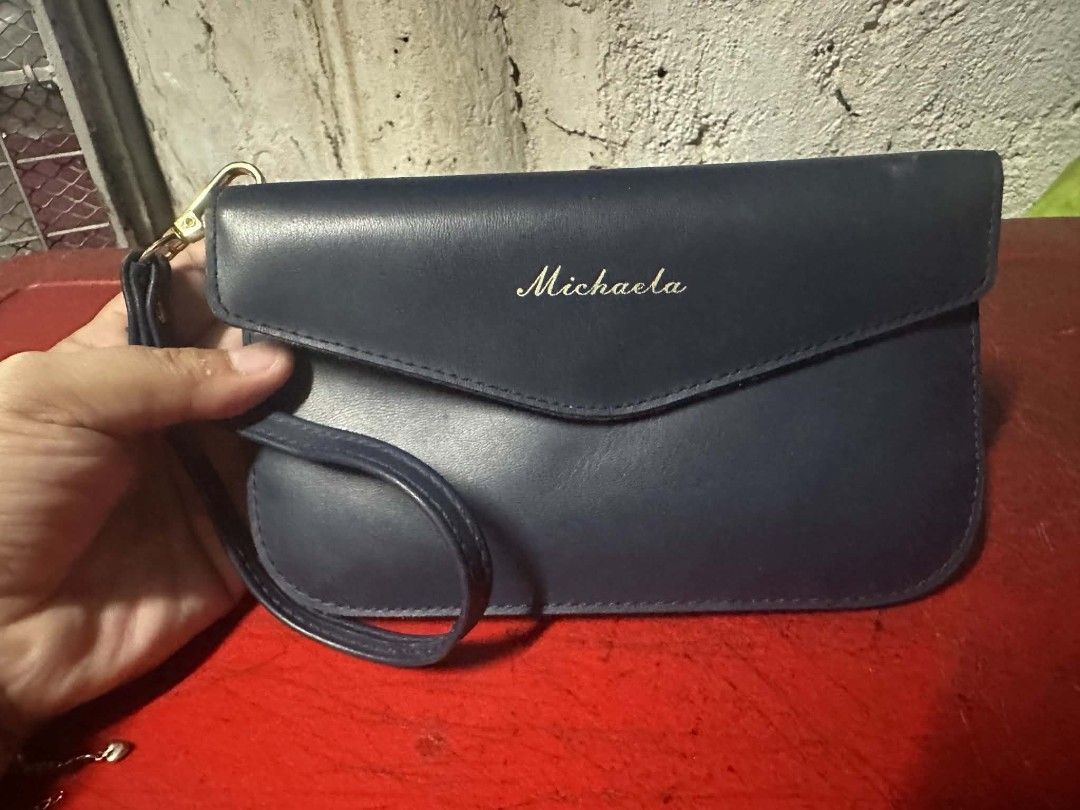 Navy Blue Clutch Bag with "Michaela" Personalization (Category: Clutches) located in Caloocan City. Submitted by rame_finds (Listing ID 1463296398, Image 1). Description: - Chic navy blue clutch bag - Detachable wrist strap for convenience - Elegant gold clasp closure - "Michaela" embroidered in gold on the front flap - Ideal for evening events or as a travel organizer - Ready for its new owner.