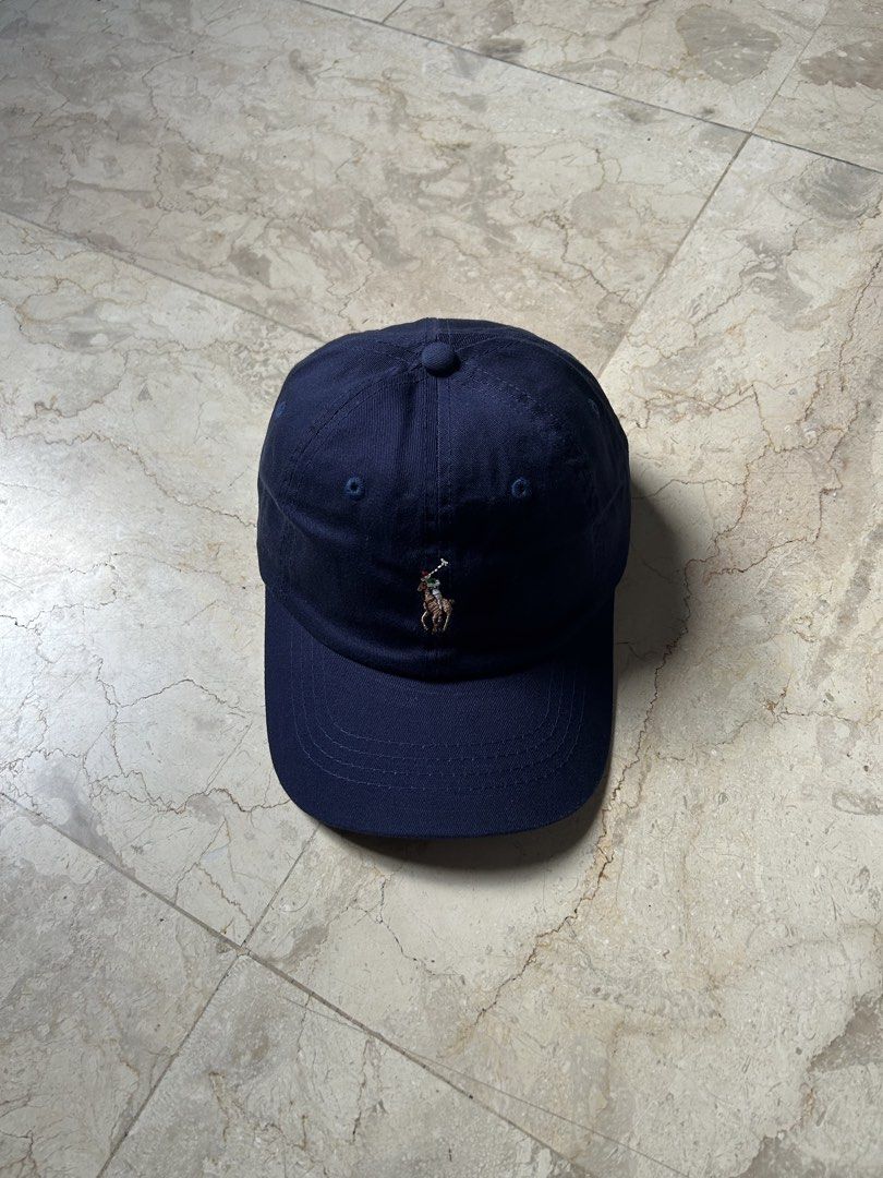 Navy Polo Ralph Lauren Cap (Category: Caps & Hats) located in Muntinlupa City. Submitted by wavesofara (Listing ID 1463126095, Image 1). Description: - Classic navy blue cap from Polo Ralph Lauren. - Iconic polo player logo embroidered on the front. - Red 'POLO' text embroidered on the back. - Adjustable strap for a comfortable fit. - Perfect for everyday wear..