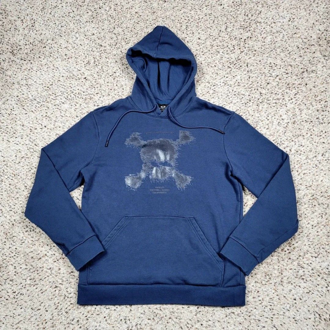 Oakley Hoodie Jacket (Category: Coats, Jackets and Outerwear) located in Manila. Submitted by icamalicdem29 (Listing ID 1463150322, Image 2). Description: teal-blue pullover hoodie featuring a distressed graphic skull and text logo detail on the chest, along with a front kangaroo pocket.