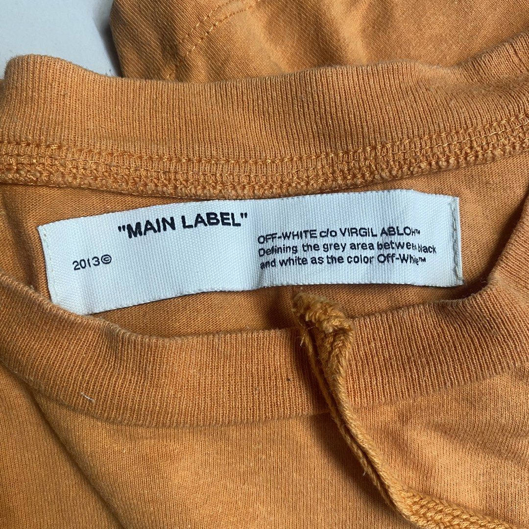 Off-White "Main Label" Orange Graphic T-Shirt (Category: Tshirts & Polo Shirts ) located in Camiling. Submitted by camthrift_2024 (Listing ID 1463166184, Image 3). Description: OFF WHITE TEE↗️ 23x30.5 COLOR RATE: 9/10 ISSUE:hairline,minimal fade print 350₱ SHIP NOW OPEN FOR TERMS UNLI VOUCH GCASH JNT CAMILING, TARLAC📌 - Orange Off-White T-shirt - Size: XS/TP - Iconic crossed arrows graphic on back - Smaller "OFF" graphic on front - Material: 100