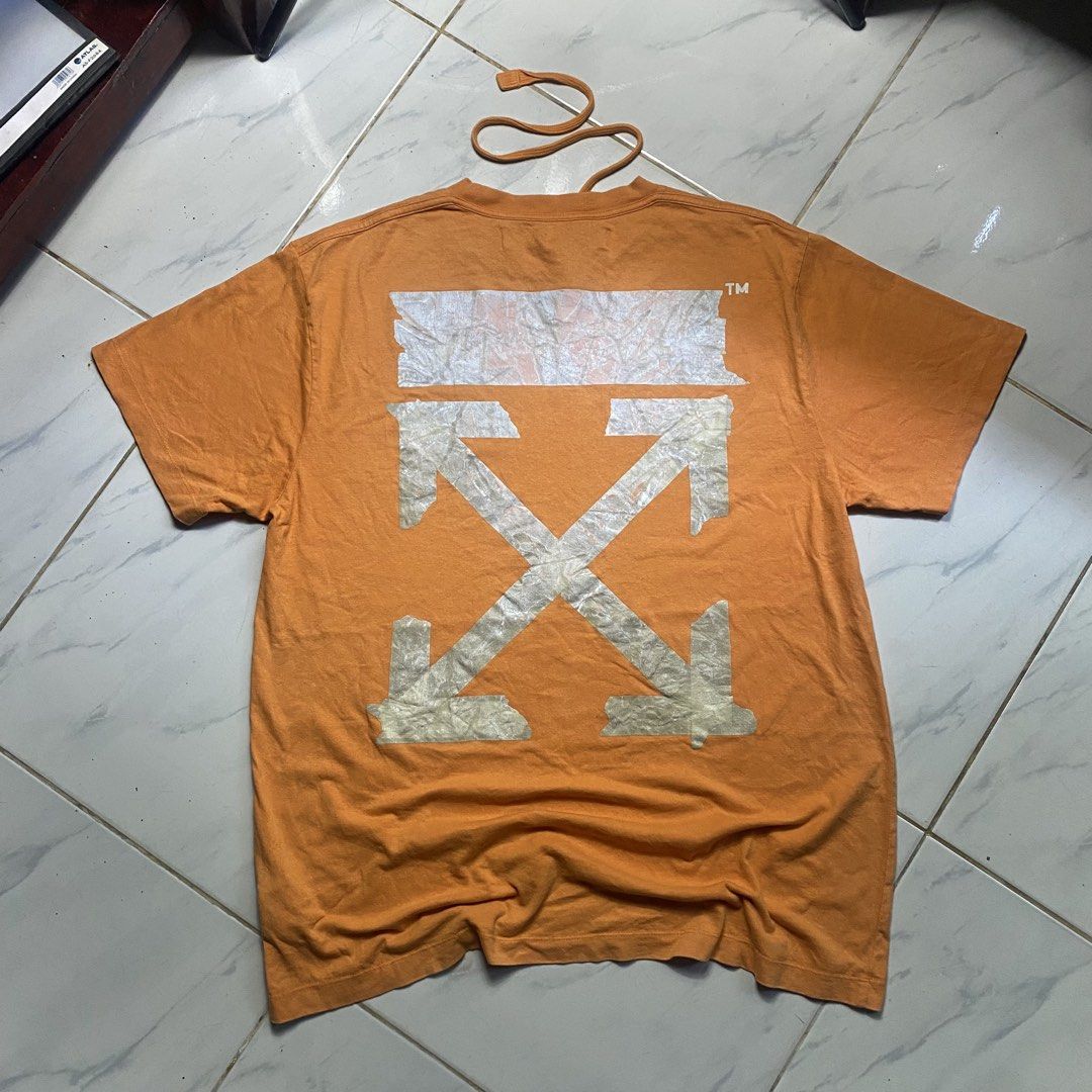 Off-White "Main Label" Orange Graphic T-Shirt (Category: Tshirts & Polo Shirts ) located in Camiling. Submitted by camthrift_2024 (Listing ID 1463166184, Image 1). Description: OFF WHITE TEE↗️ 23x30.5 COLOR RATE: 9/10 ISSUE:hairline,minimal fade print 350₱ SHIP NOW OPEN FOR TERMS UNLI VOUCH GCASH JNT CAMILING, TARLAC📌 - Orange Off-White T-shirt - Size: XS/TP - Iconic crossed arrows graphic on back - Smaller "OFF" graphic on front - Material: 100