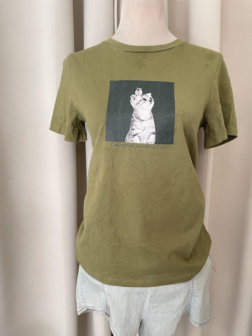 Olive Green Cat Graphic Tee (Category: Shirts) located in Cainta. Submitted by zlove111 (Listing ID 1463178061, Image 1). Description: - Olive green t-shirt - Features a funny cat graphic with text: 'CAN ANYONE ELSE HEAR THAT?' - Short sleeves and crew neck design - Made from a comfortable cotton blend - Ideal for casual wear - Easily pairs with jeans or shorts.
