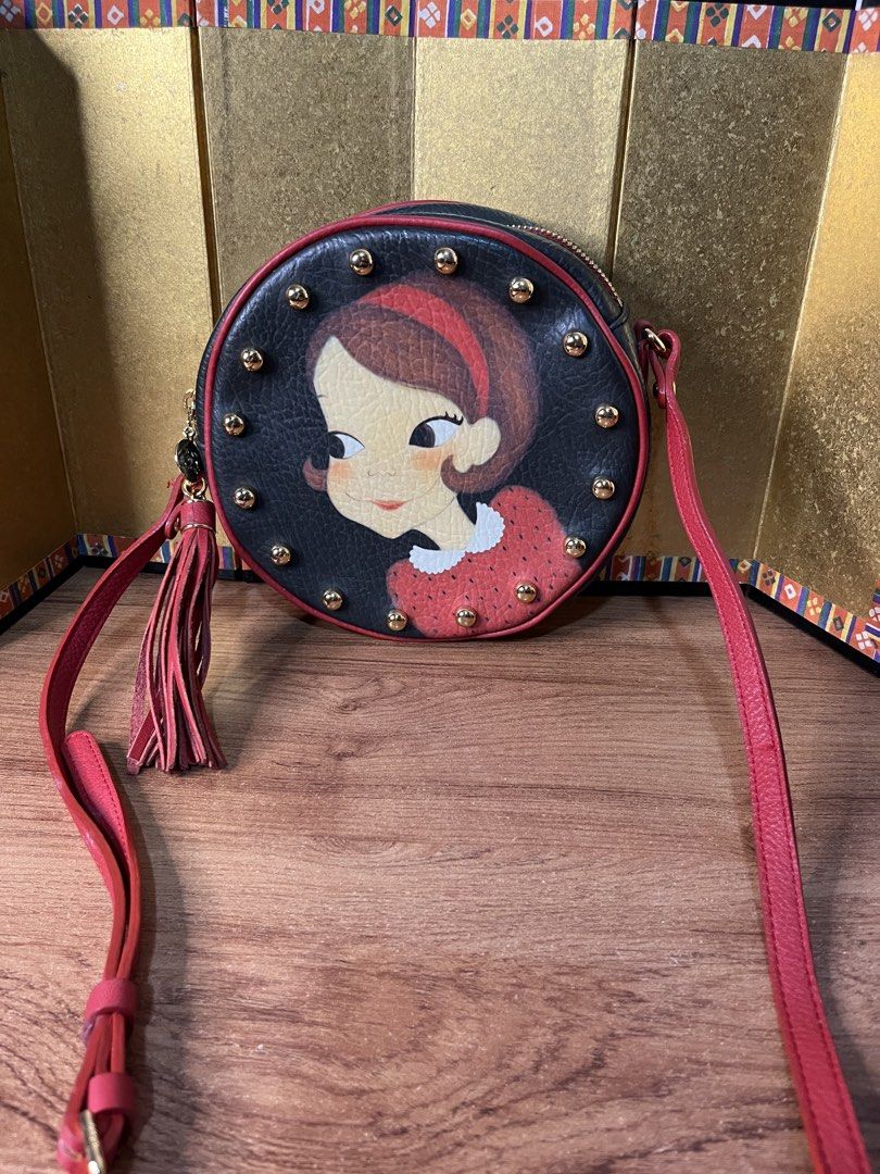 Original YOUK SHIM WON Sling Bag (Category: Cross-body Bags) located in Gapan. Submitted by lunashop14 (Listing ID 1463145084, Image 1). Description: Collector’s piece! 🎨✨ Selling this gorgeous authentic Youk Shim Won round crossbody bag. It features the brand’s iconic, playful character portrait framed by edgy gold-toned studs and a statement red leather tassel. Perfect for adding a pop of color and artistic flair to any outfit.🎒 Compact round