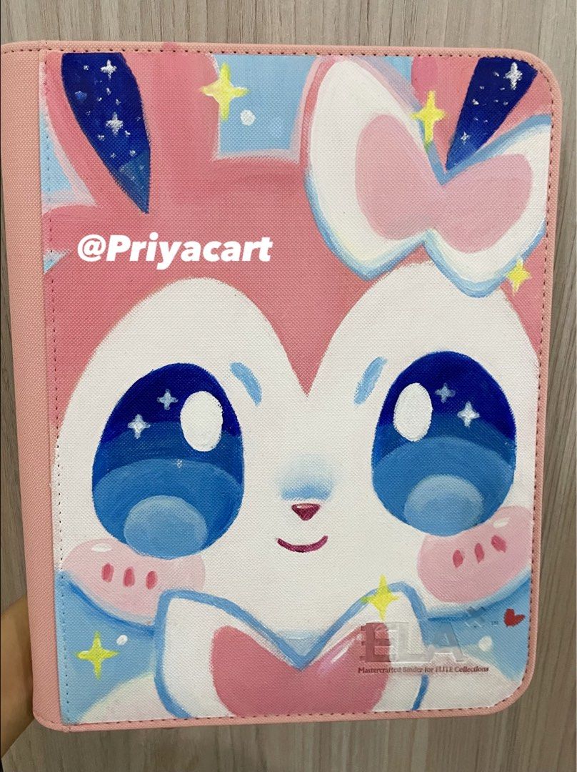 Pokemon Sylveon 4- Pocket Toploader Binder cute (Category: Trading Cards Accessories) located in Zamboanga. Submitted by priyacart (Listing ID 1463221043, Image 2). Description: Hi! ₍^. .^₎⟆ 🩵Hand-painted Pokemon Sylveon 4 pocket toploader binder 🩵Brand : ELA ✨ Acrylic and Matte protective topcoat 🩵Designed to hold toploaders for card protection 🩵Perfect for Pokemon CuteMon collectors like mee Open for commissions dm me 🤭✨ 𐔌՞ ܸ.ˬ.ܸ՞𐦯 Mod: 