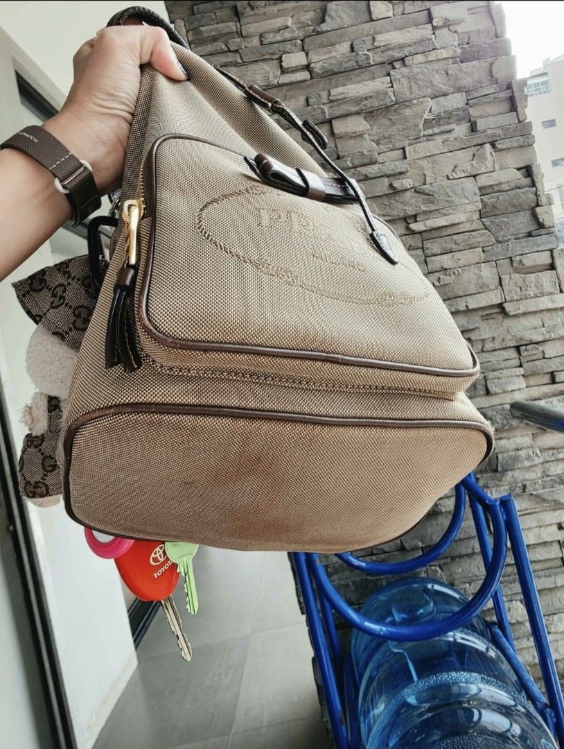 Prada Canvas Bucket Bag with Leather Trim (Category: Luxury Bags & Wallets) located in Lapu Lapu. Submitted by margaux099 (Listing ID 1463224227, Image 3). Description: - Authentic Prada bucket bag - Color: Beige canvas with brown leather details - Closure: Drawstring - Exterior: Front zip pocket - Includes: Cute keychain charm - Style: Great for everyday use - Capacity: Plenty of space inside -with sign of usage.