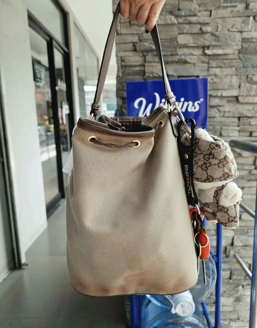 Prada Canvas Bucket Bag with Leather Trim (Category: Luxury Bags & Wallets) located in Lapu Lapu. Submitted by margaux099 (Listing ID 1463224227, Image 2). Description: - Authentic Prada bucket bag - Color: Beige canvas with brown leather details - Closure: Drawstring - Exterior: Front zip pocket - Includes: Cute keychain charm - Style: Great for everyday use - Capacity: Plenty of space inside -with sign of usage.