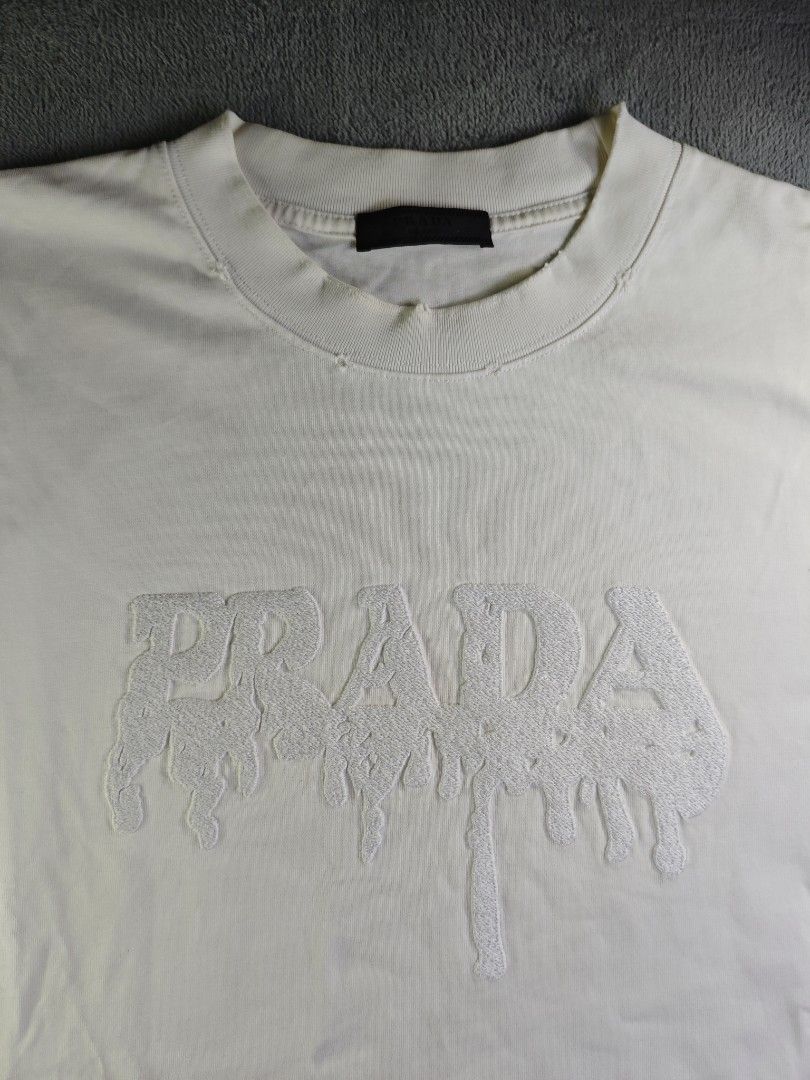 Prada Milano Dripping Carpetized Logo Distressed White Crew Neck Tee (Category: Tshirts & Polo Shirts ) located in San Pedro. Submitted by chronothrift2ndacc (Listing ID 1463183947, Image 2). Description: - Size: XL (W23 x 30L) - Condition: 9.2/10 - Color Rate: 9/10 - Flaws: ❌❌❌ MOD: J&T Express / Lalamove / Meet MOP: Gcash / Bank Transfer.