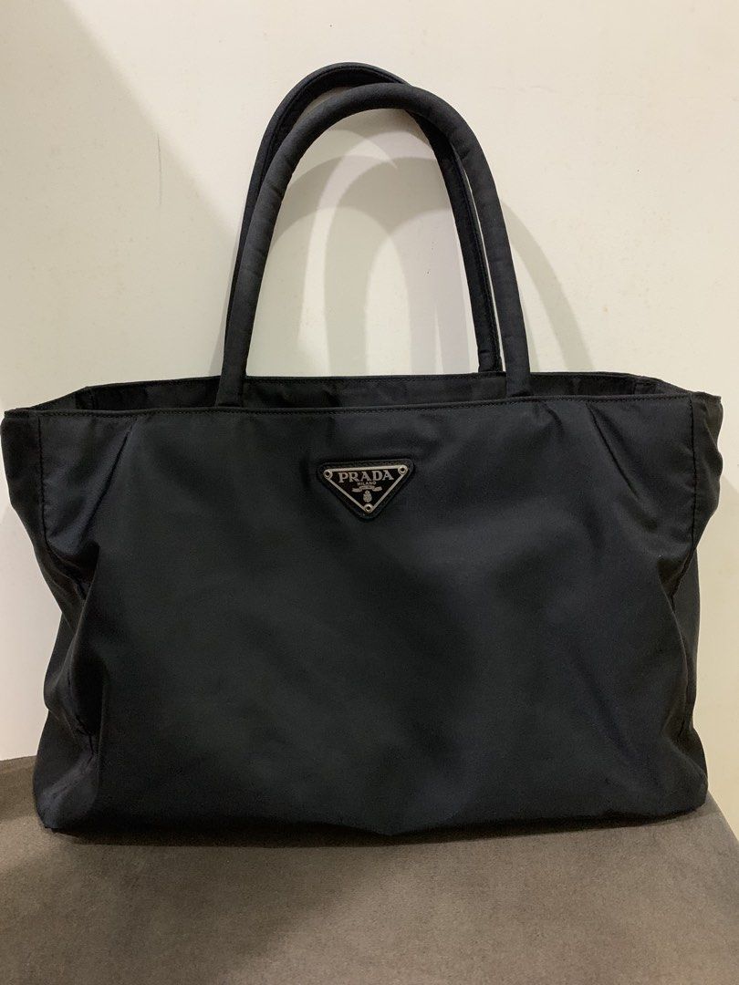 Prada Tessuto (Category: Luxury Bags & Wallets) located in Muntinlupa City. Submitted by mabelleadr46801 (Listing ID 1463246320, Image 2). Description: Prada Tessuto Nylon Tote Bag in black. This classic style features Prada’s signature durable and lightweight nylon material, dual top handles, and the iconic inverted enamel triangle logo plaque prominently on the front W 13” H 9”.