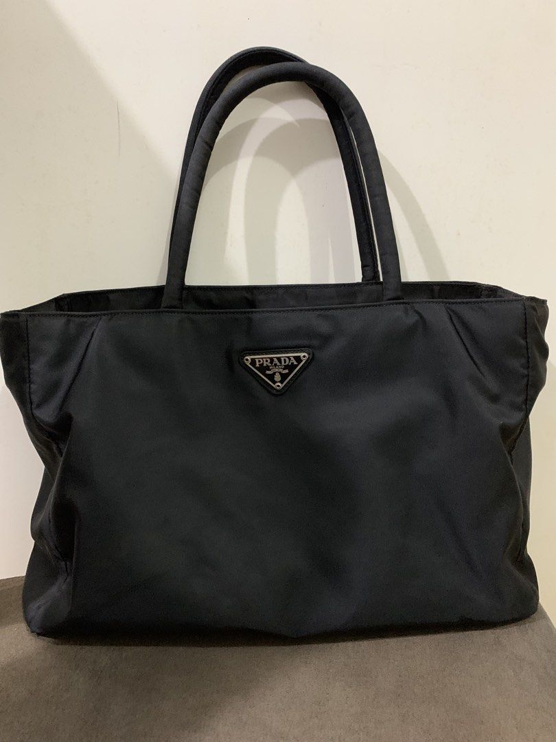 Prada Tessuto (Category: Luxury Bags & Wallets) located in Muntinlupa City. Submitted by mabelleadr46801 (Listing ID 1463246320, Image 1). Description: Prada Tessuto Nylon Tote Bag in black. This classic style features Prada’s signature durable and lightweight nylon material, dual top handles, and the iconic inverted enamel triangle logo plaque prominently on the front W 13” H 9”.