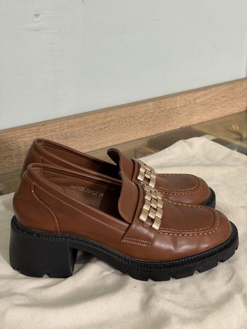 Rock&Rose Brown Loafers (Category: Loafers) located in Magarao. Submitted by coleeloves_ (Listing ID 1463141682, Image 2). Description: - Stylish brown leather loafers - Size 38 - Chunky black sole for comfort and trend - Elegant gold chain detail across the vamp - Modern square toe design - Ideal for everyday wear - Minor scuffs present, as pictured.