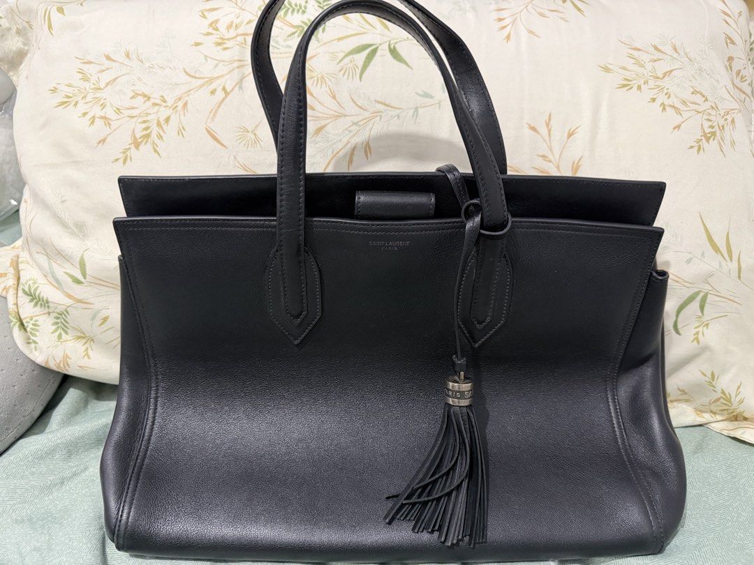 Saint Laurent Black Leather Tote Bag (Category: Luxury Bags & Wallets) located in Manila. Submitted by ney14 (Listing ID 1463217296, Image 1). Description: - Authentic Saint Laurent black leather tote bag - Features a chic tassel detail - Embossed Saint Laurent brand name on the front - Made from soft and supple leather - Comes with original dust bag - Ideal for everyday use or travel -comes with care card and authentication card -with tassel, du