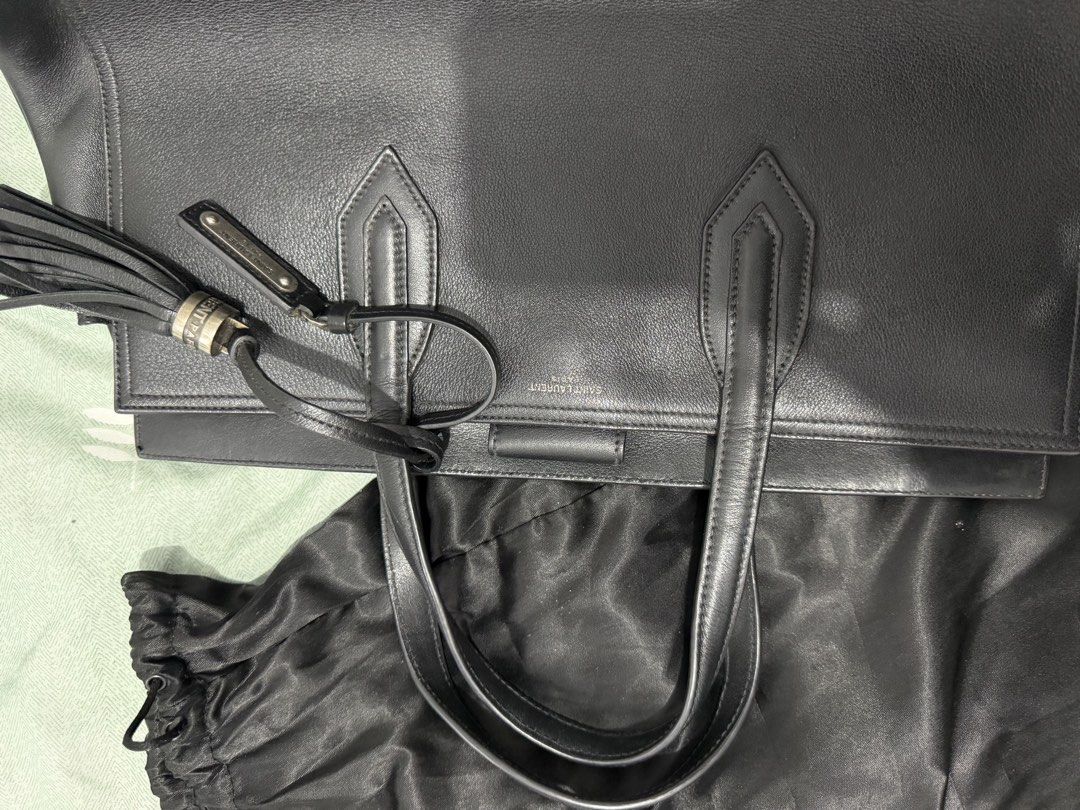 Saint Laurent Black Leather Tote Bag (Category: Luxury Bags & Wallets) located in Manila. Submitted by ney14 (Listing ID 1463217296, Image 3). Description: - Authentic Saint Laurent black leather tote bag - Features a chic tassel detail - Embossed Saint Laurent brand name on the front - Made from soft and supple leather - Comes with original dust bag - Ideal for everyday use or travel -comes with care card and authentication card -with tassel, du