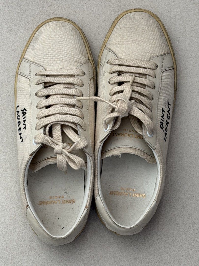 Saint Laurent Canvas Sneakers (Category: Sneakers) located in Taguig. Submitted by anxmz (Listing ID 1462266324, Image 1). Description: - Authentic Saint Laurent canvas sneakers - Natural beige color with iconic black logo detail - Classic lace-up closure - Durable rubber sole - Perfect for everyday casual style - Shows some signs of wear on the sole and canvas, adding character.