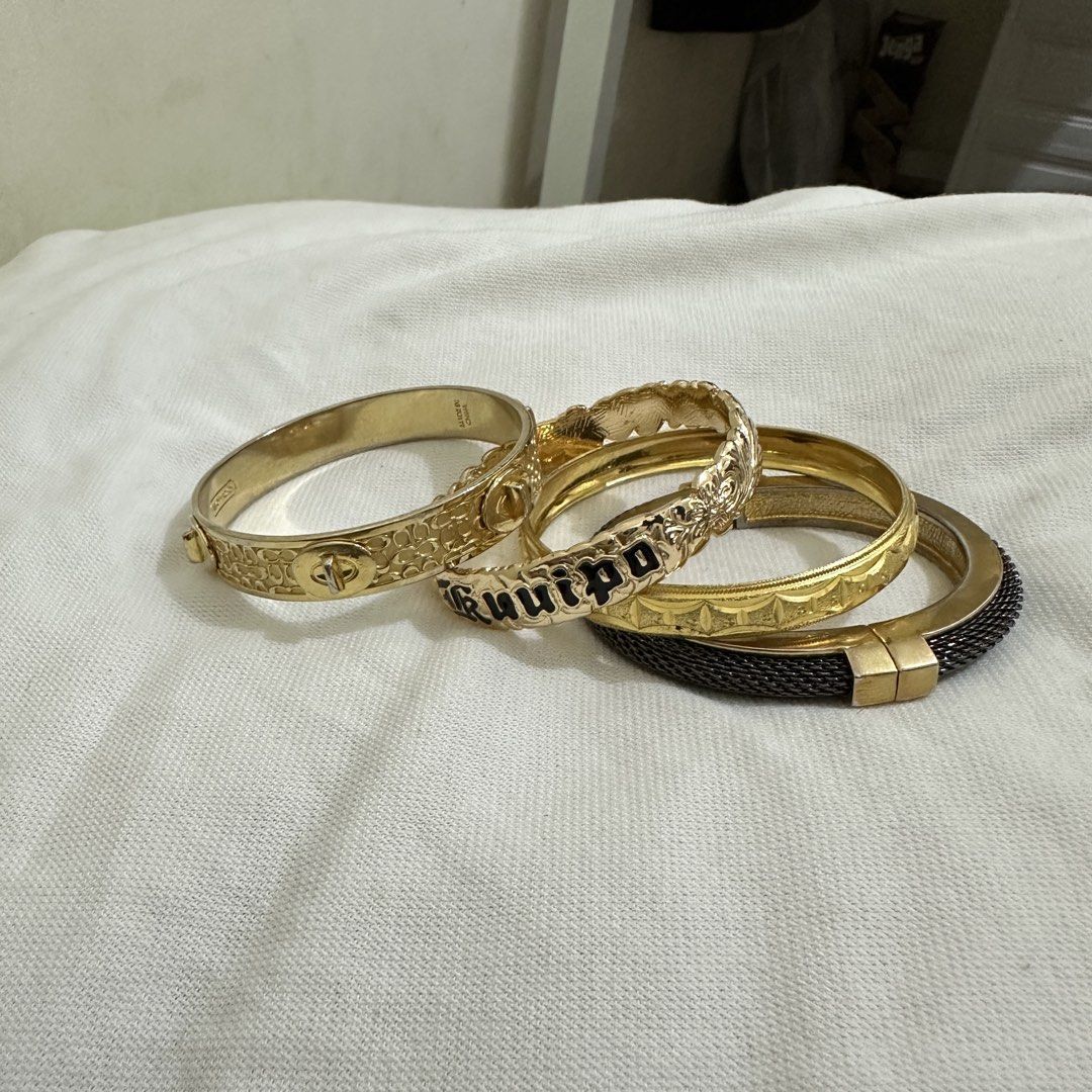 Set of 4 Gold Tone Bracelets Bundle (Category: Bracelets) located in Bulacan. Submitted by enne_123 (Listing ID 1463238743, Image 1). Description: - Set of 4 gold-tone hinged bangles - One bangle features a black 'Guilpo' inscription - Another bangle has a unique mesh-like texture - Versatile for stacking or wearing separately - Sold as a complete set.