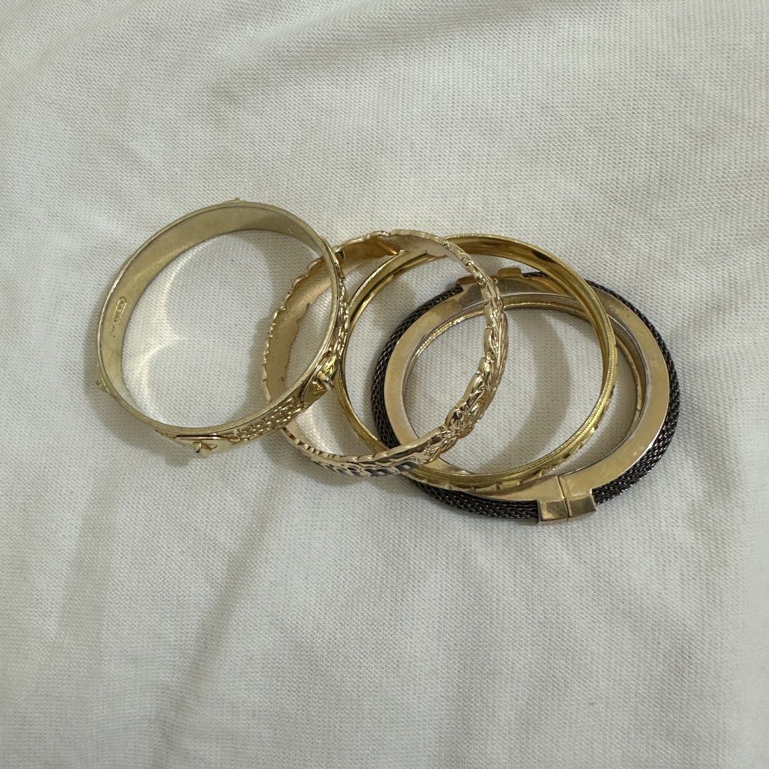 Set of 4 Gold Tone Bracelets Bundle (Category: Bracelets) located in Bulacan. Submitted by enne_123 (Listing ID 1463238743, Image 2). Description: - Set of 4 gold-tone hinged bangles - One bangle features a black 'Guilpo' inscription - Another bangle has a unique mesh-like texture - Versatile for stacking or wearing separately - Sold as a complete set.