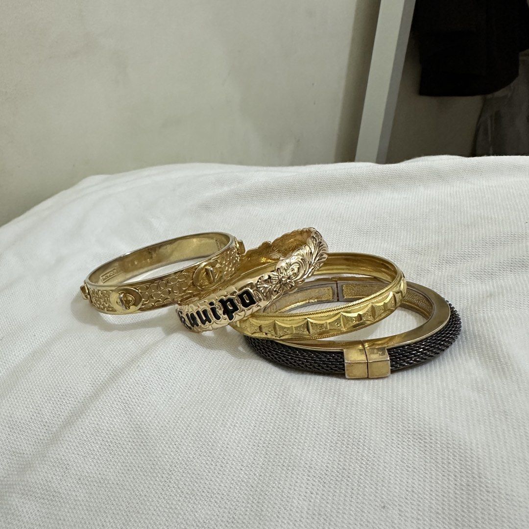 Set of 4 Gold Tone Bracelets Bundle (Category: Bracelets) located in Bulacan. Submitted by enne_123 (Listing ID 1463238743, Image 3). Description: - Set of 4 gold-tone hinged bangles - One bangle features a black 'Guilpo' inscription - Another bangle has a unique mesh-like texture - Versatile for stacking or wearing separately - Sold as a complete set.