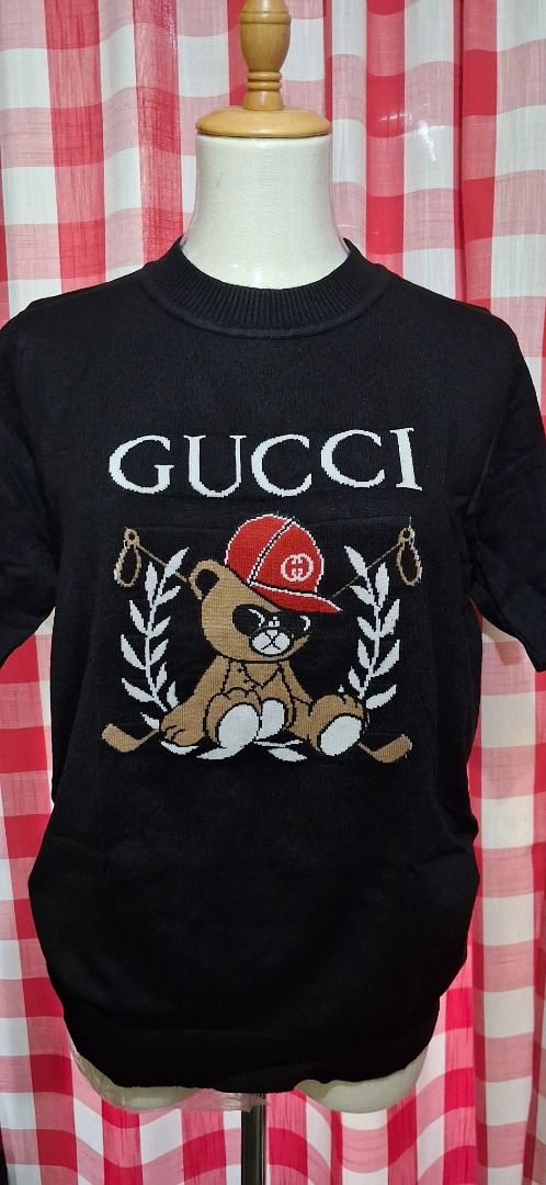 Teddy Bear Knit Sweater (Category: Coats, Jackets and Outerwear) located in Manila. Submitted by katkween23 (Listing ID 1463221582, Image 1). Description: - Black knit sweater - Features iconic Gucci logo - Adorable teddy bear graphic wearing a red cap - Laurel wreath detail on the sides - Short sleeves - Ideal for casual wear.