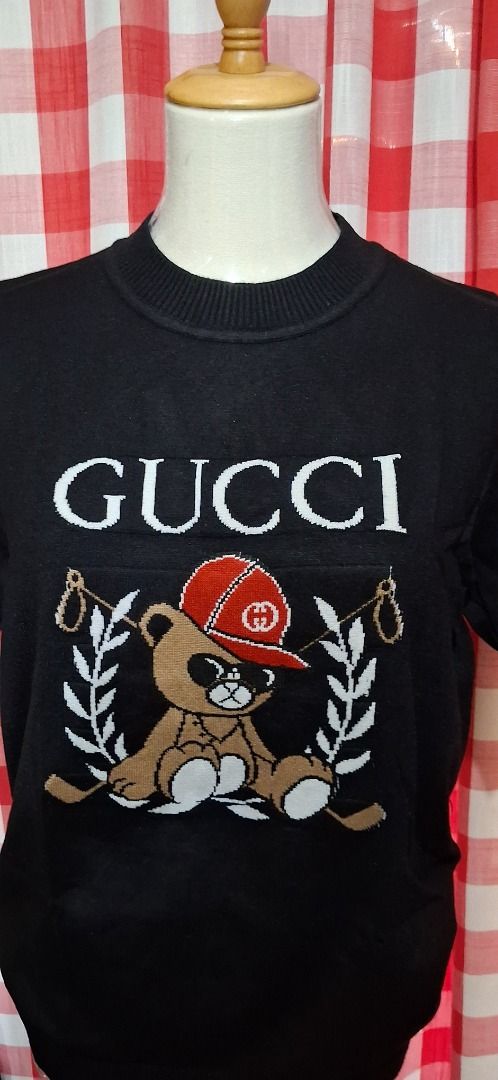 Teddy Bear Knit Sweater (Category: Coats, Jackets and Outerwear) located in Manila. Submitted by katkween23 (Listing ID 1463221582, Image 3). Description: - Black knit sweater - Features iconic Gucci logo - Adorable teddy bear graphic wearing a red cap - Laurel wreath detail on the sides - Short sleeves - Ideal for casual wear.