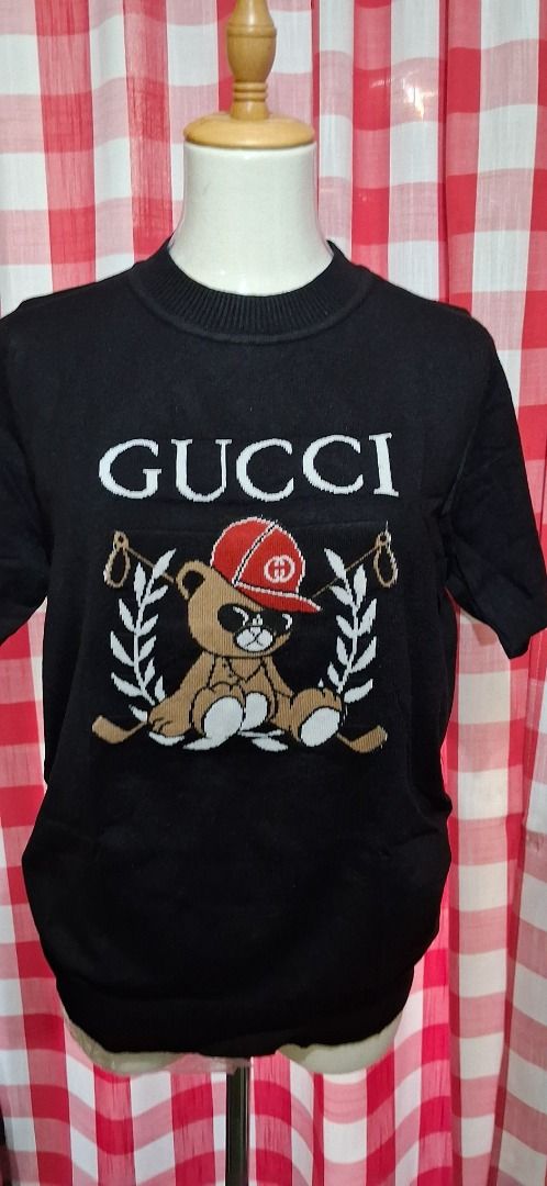 Teddy Bear Knit Sweater (Category: Coats, Jackets and Outerwear) located in Manila. Submitted by katkween23 (Listing ID 1463221582, Image 2). Description: - Black knit sweater - Features iconic Gucci logo - Adorable teddy bear graphic wearing a red cap - Laurel wreath detail on the sides - Short sleeves - Ideal for casual wear.